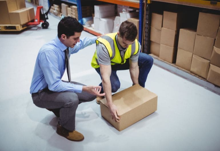 A person being shown how to safley lift a box